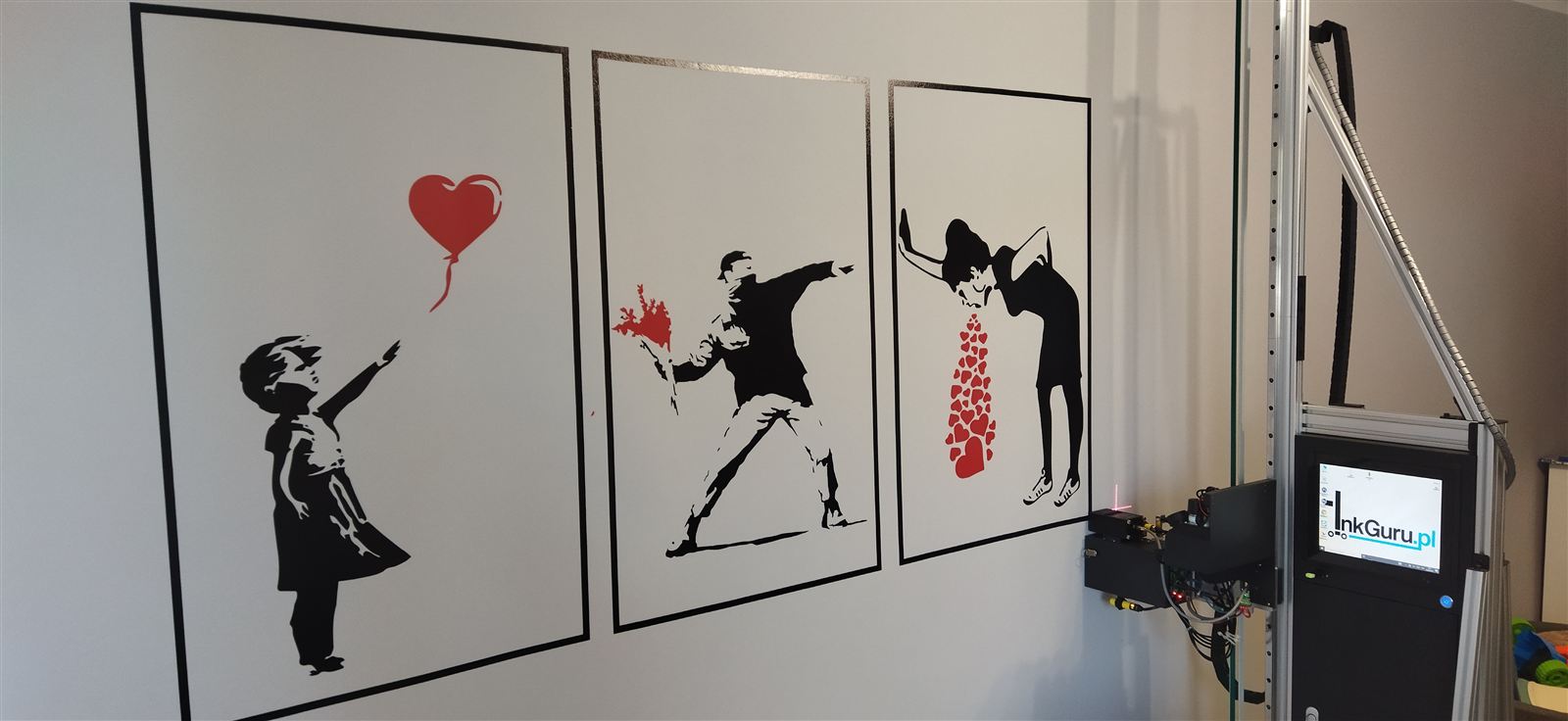 Tryptyk w stylu Banksy'ego wydrukowany na ścianie, obok drukarka ścienna